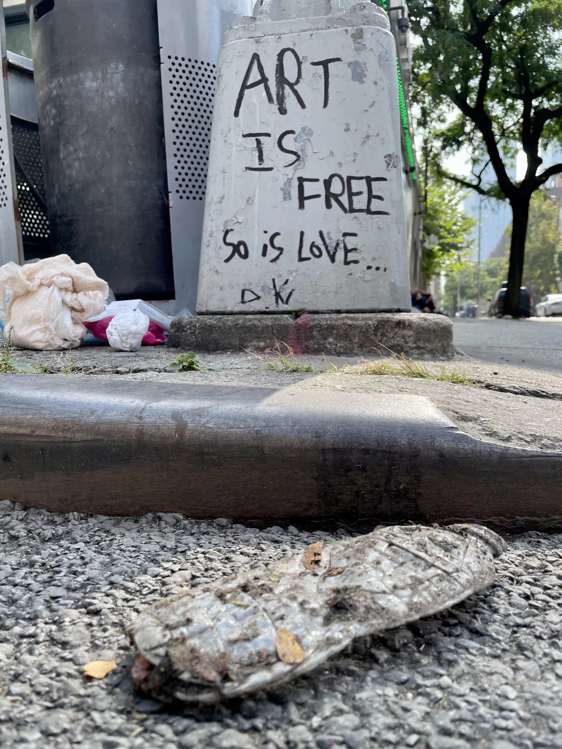 Graffiti on a New York City lamppost declaring "Art is free, so is love."